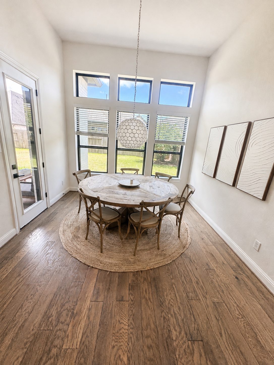 A sunlit dining room with a round table and tall windows