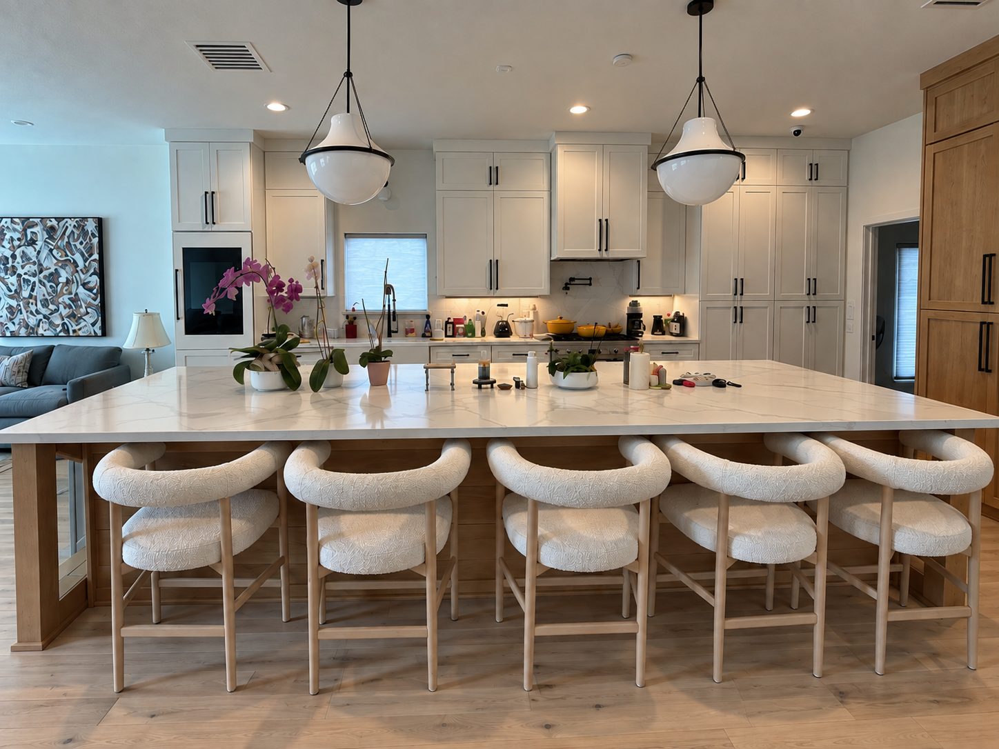 A freshly reset kitchen island with white stools and pendant lights